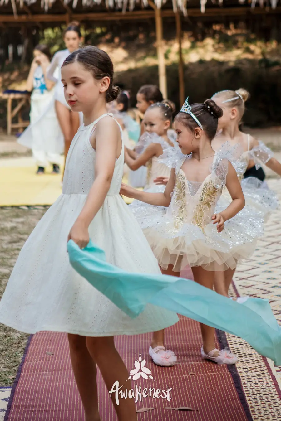 Girl in white dress twirling teal scarf.