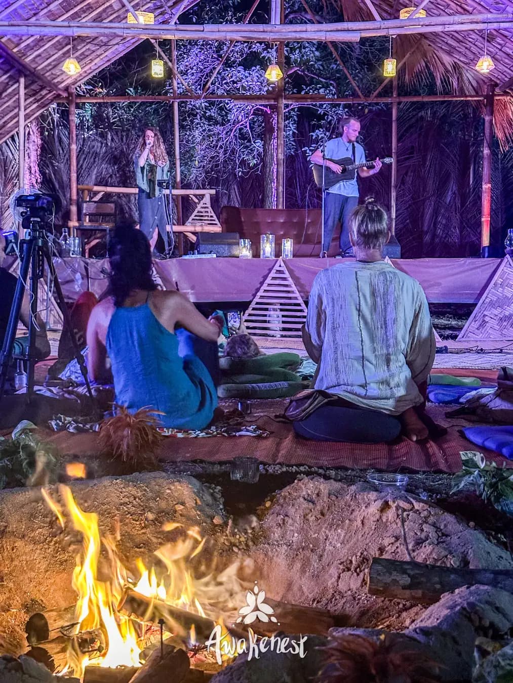 Musicians perform on stage at night bonfire.