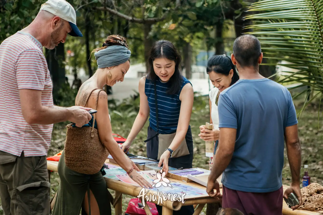 Group gathers around craft table outdoors.
