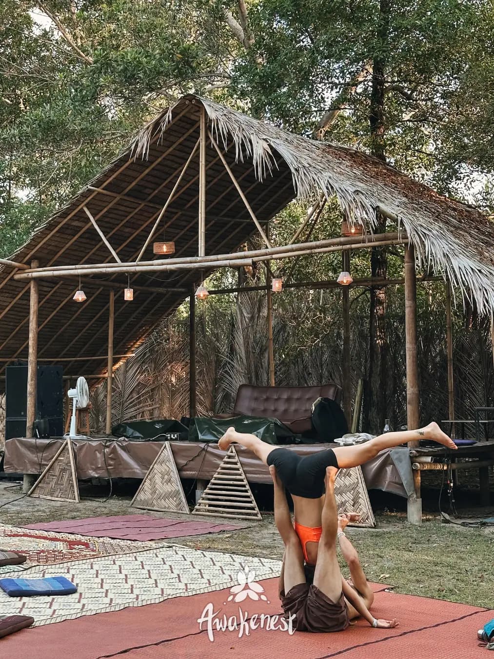 Acro-yoga pair balancing outside forest dome.