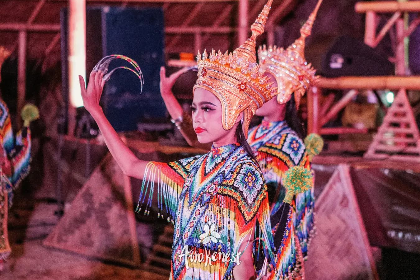 Dancer in ornate gold headdress performs indoors.