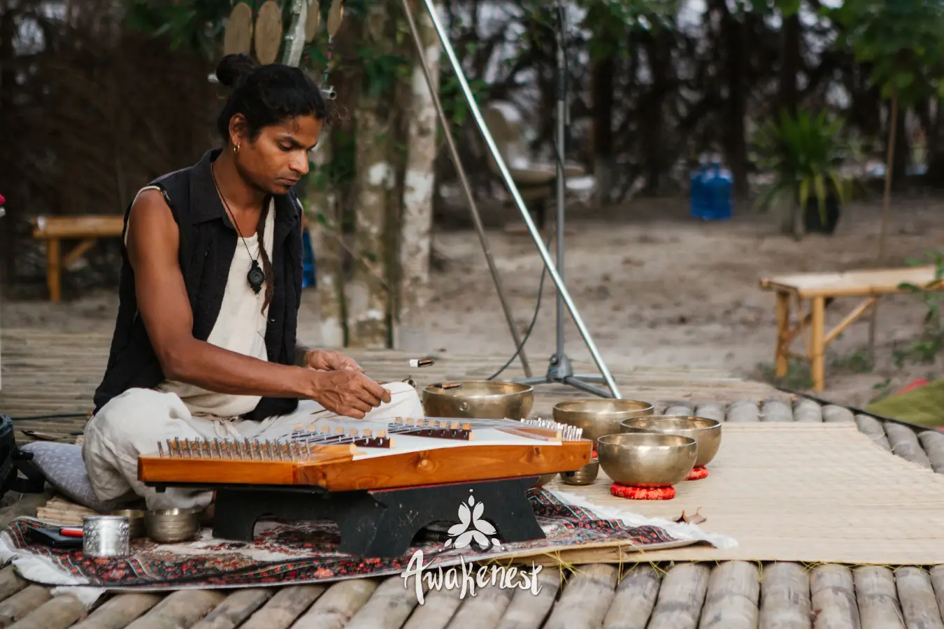Man plays handpan surrounded by singing bowls.