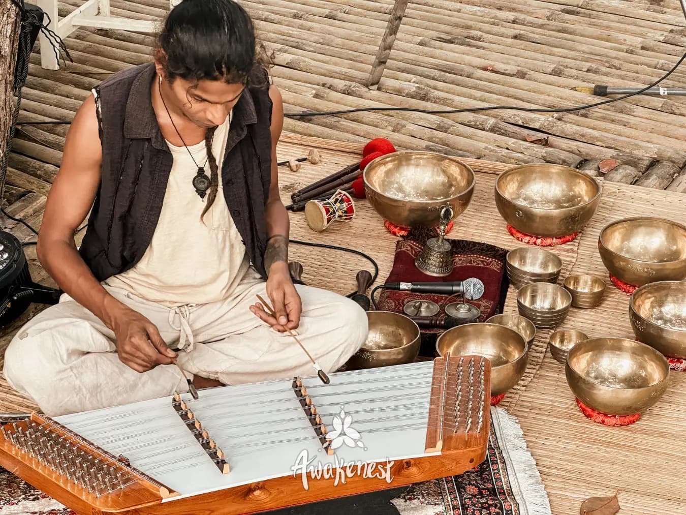 Musician plays khim beside singing bowls.