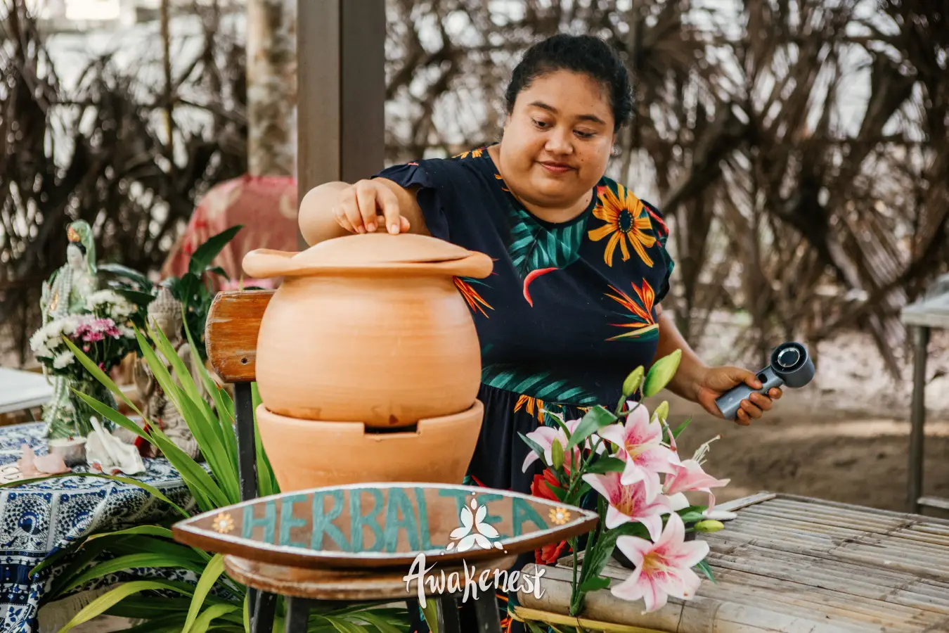 Woman demonstrates herbal tea preparation at stall.
