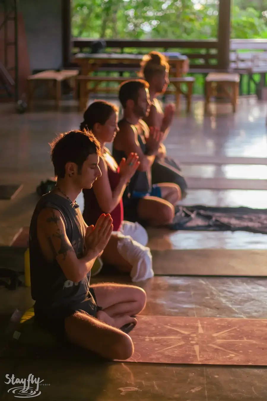 Two participants sit facing one another with palms together in the evening pavilion.