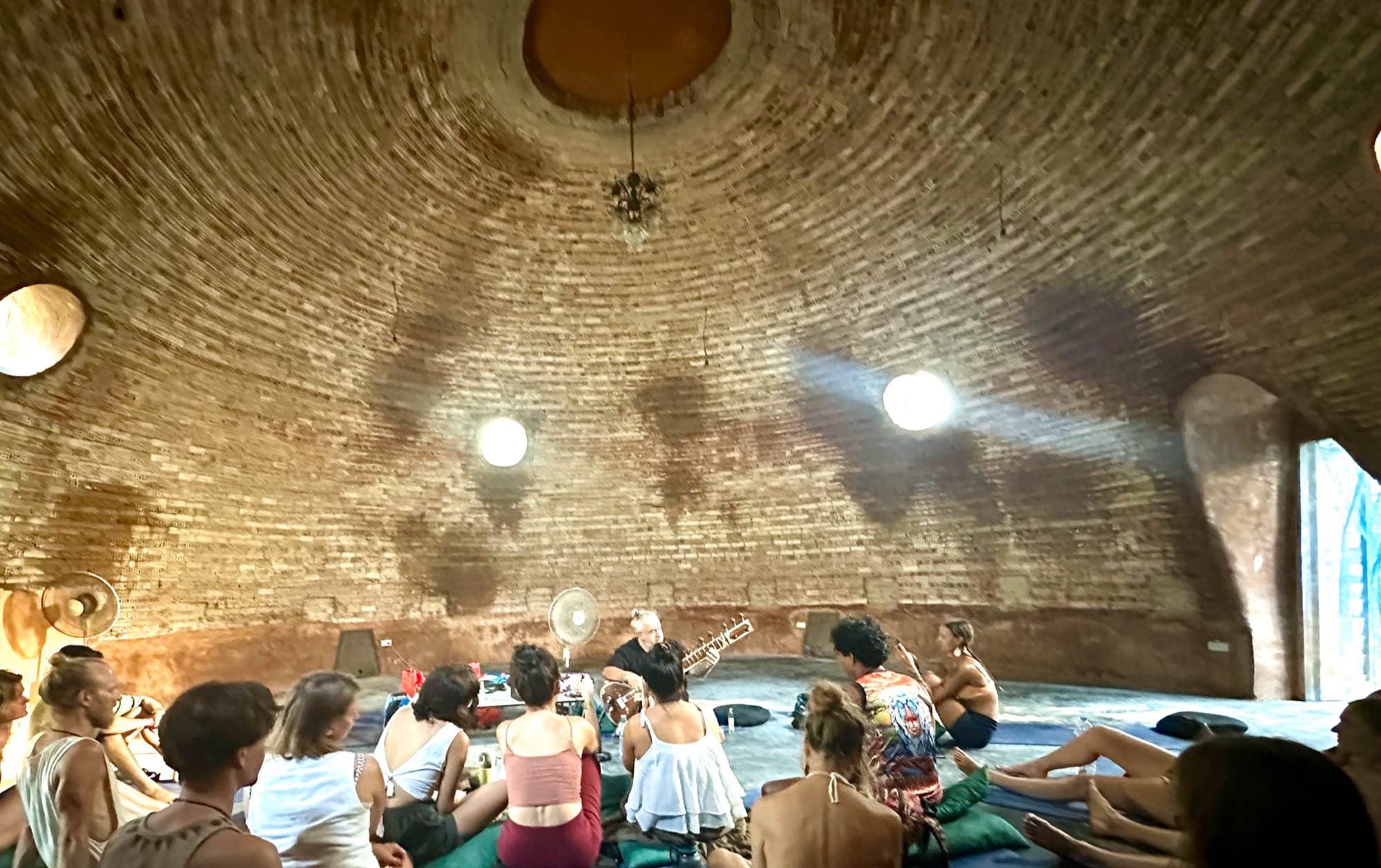A quiet gathering seated in a circle inside the earthen Dome