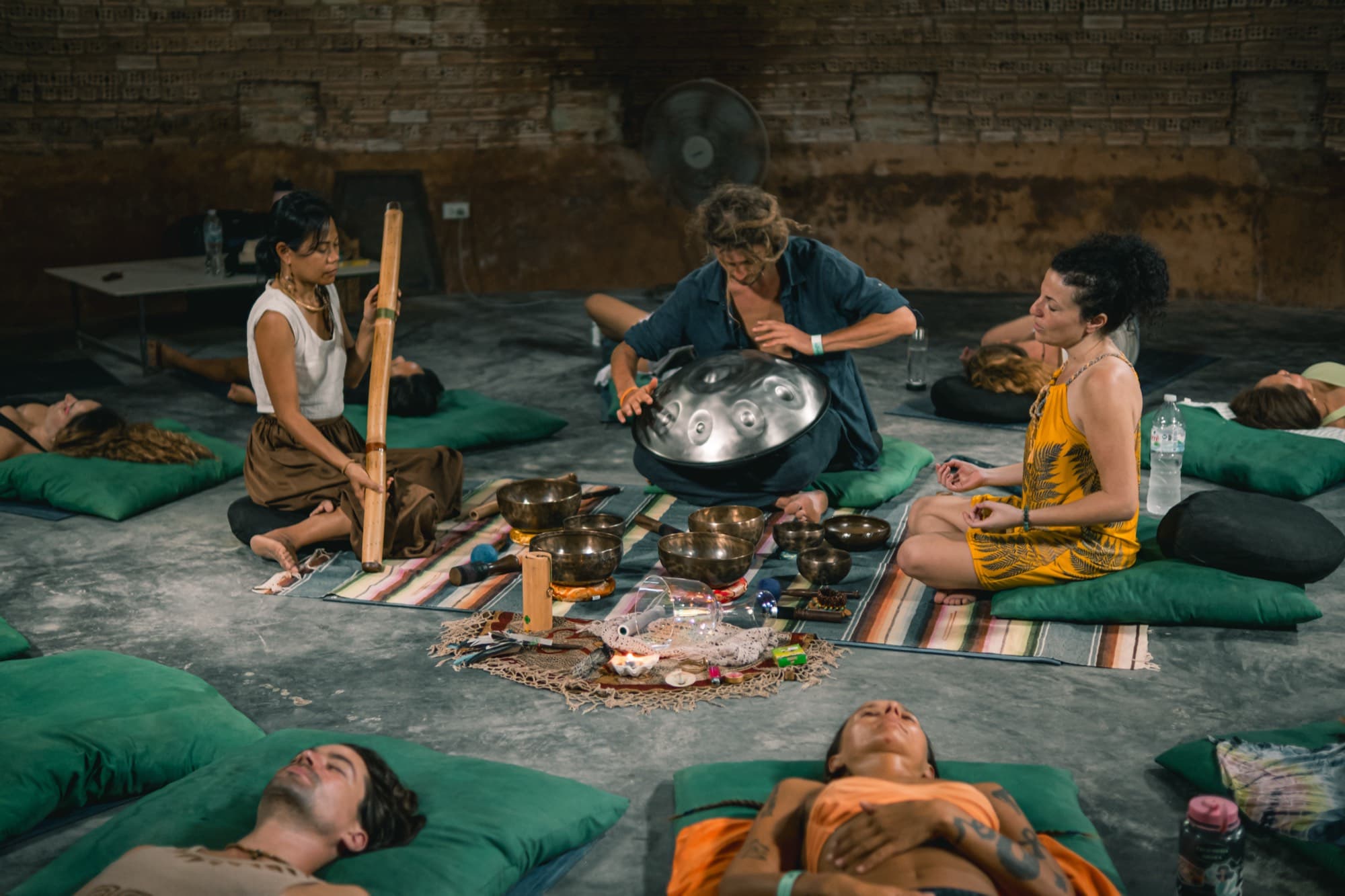 Three Awakenest sound practitioners holding a clearing session around resting participants