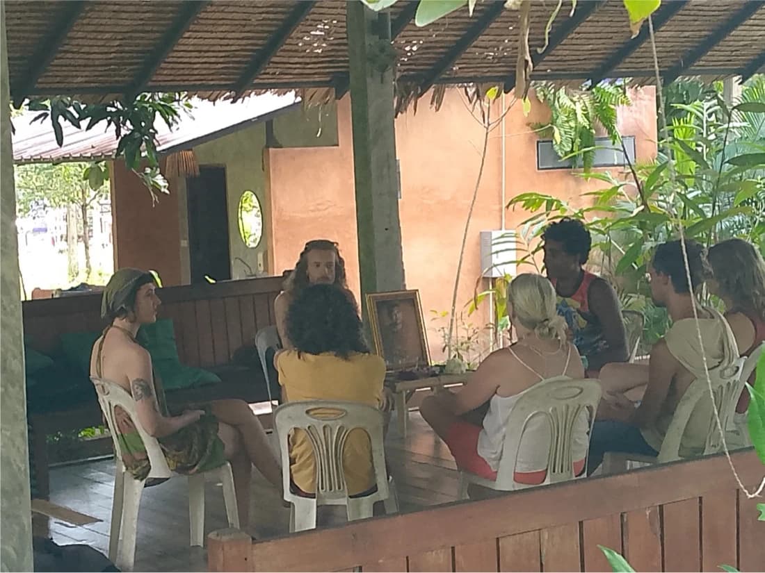 A group seated on chairs in an open sided pavilion, one person speaking to the others.