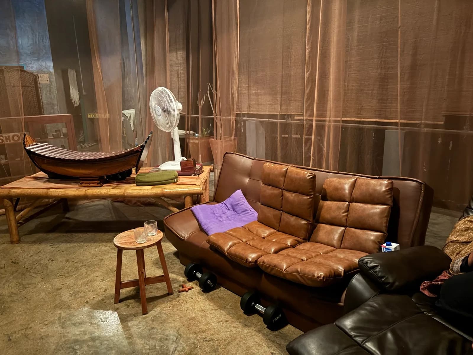 A leather sofa, a wooden stool and a Thai xylophone on a bamboo daybed in the lounge corner of the room.